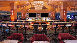 A bar area with multiple stools, a bar counter, and a chandelier. - Masquerade Tower at Rio Hotel & Casino (Las Vegas)