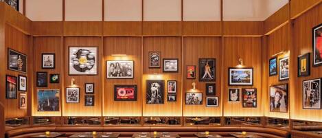 A restaurant with wooden panel walls, framed pictures, and a variety of seating options including booths and tables.