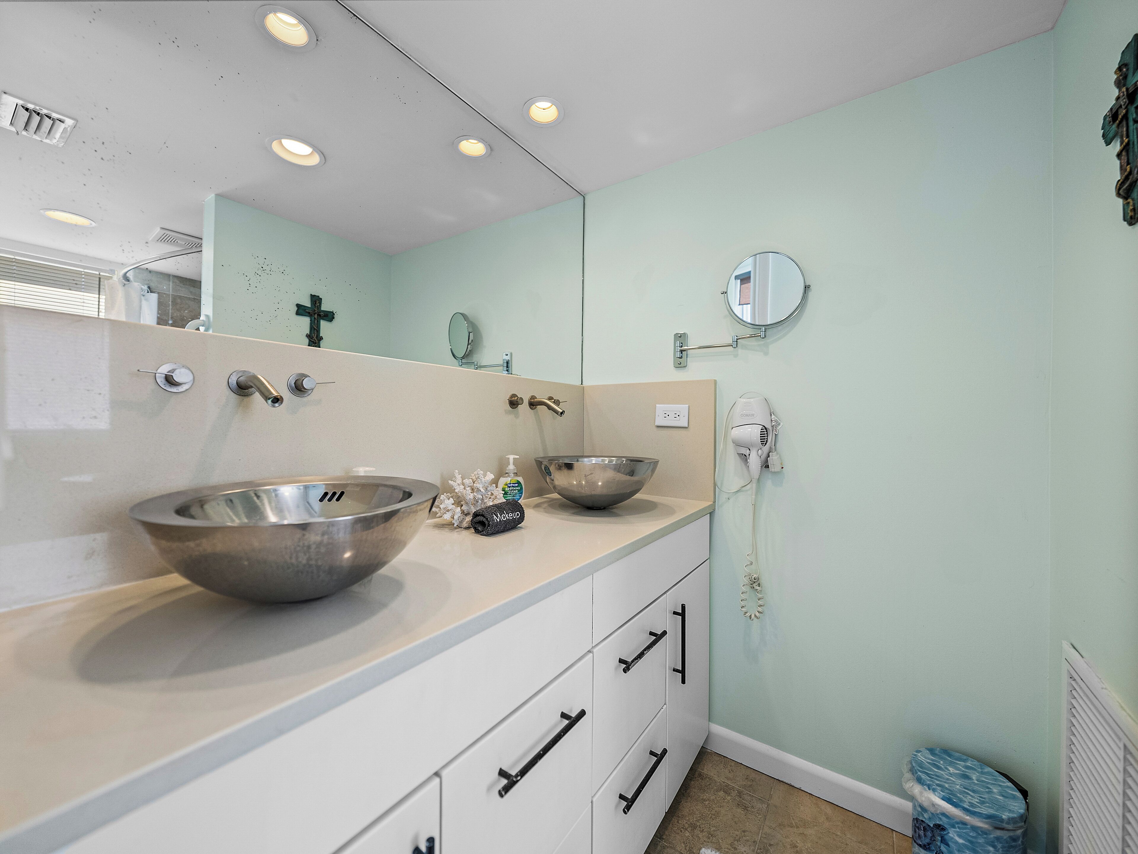 A bathroom with a large sink, two mirrors, a hairdryer, and a towel rack.