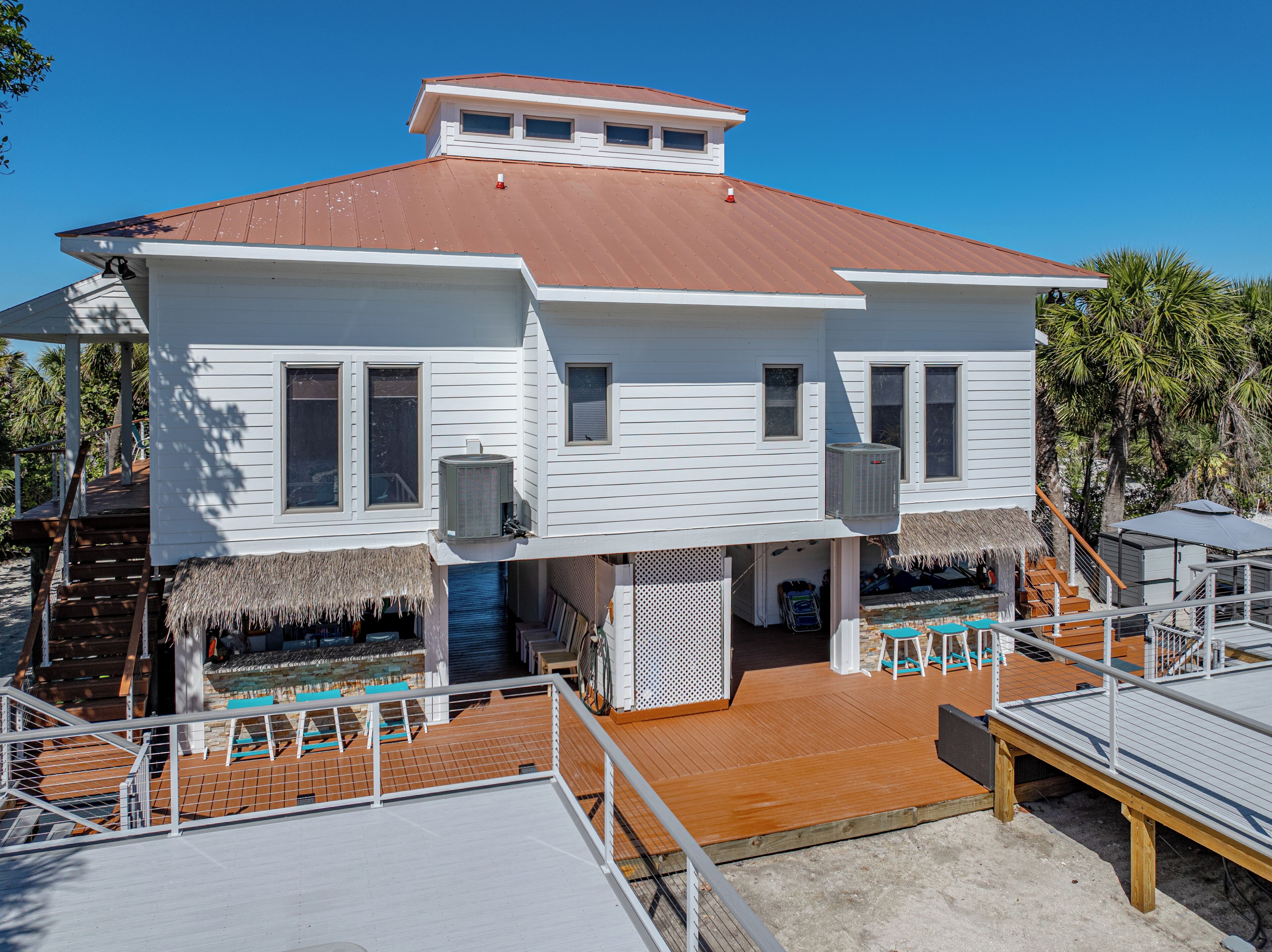 A two-story house with a red roof, white siding, and a wooden deck.