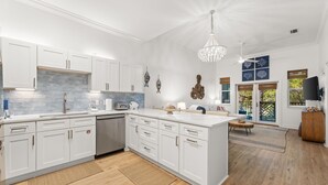 A modern kitchen with white cabinetry, a central island, and a chandelier.