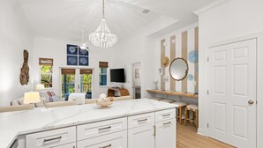 A spacious kitchen with a marble countertop, a chandelier, and a dining area with a wooden table and chairs.