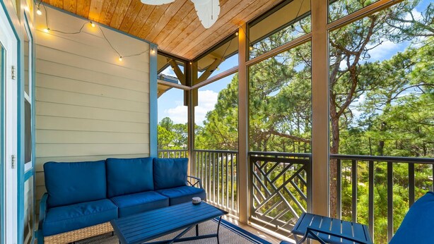 A covered outdoor area with a blue sofa, a small table, and a chair.