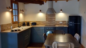 Una cocina con vigas de madera, salpicadero de ladrillo y una mesa de comedor con sillas.