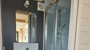 A modern bathroom with a glass-enclosed shower, a white sink, and a mirror above it. - Tiny House with private Spa (Boigny-sur-Bionne)