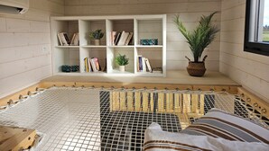 A cozy room with a hammock, a bookshelf, and a potted plant. - Tiny House with private Spa (Boigny-sur-Bionne)