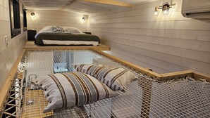 A bunk bed with a metal safety rail, a wooden headboard, and a bed with striped bedding. - Tiny House with private Spa (Boigny-sur-Bionne)