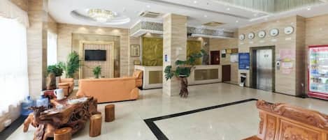Un vestíbulo de hotel con mostrador de recepción, zona de estar y una gran araña.