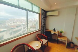 A room with a large window, a desk, a chair, and a small table. - Jinlongwan Hotel (Lianzhou)