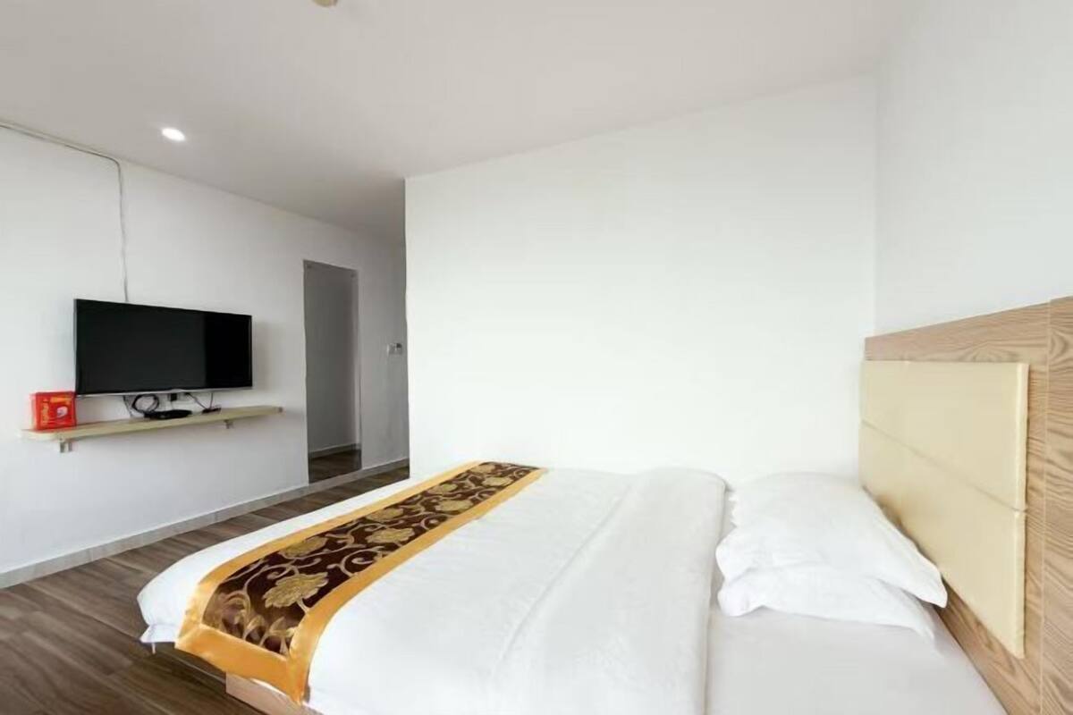 Een hotelkamer met een bed, een aan de muur bevestigde televisie en een houten hoofdeinde.