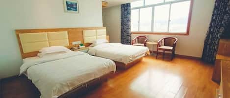 Una habitación de hotel con dos camas, una ventana con cortinas, una silla y un escritorio.