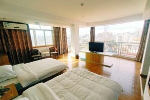 Habitación de hotel con dos camas, televisión, escritorio y vista a la ciudad.