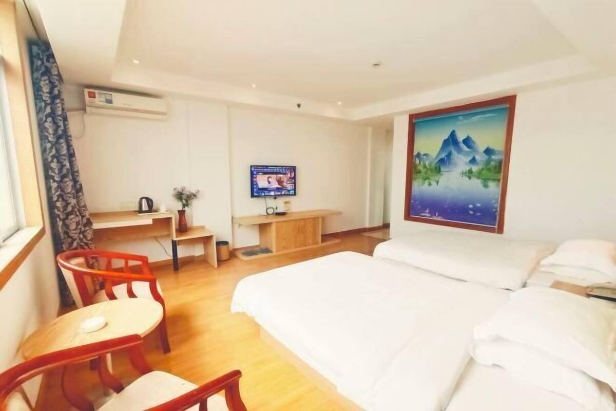 Een hotelkamer met een bed, een bureau met stoel, een televisie en een schilderij aan de muur.