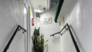 Un escalier avec un panneau d’avertissement, un pot de fleurs et une pancarte de bienvenue.