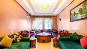 A spacious living room with a large sofa set, a round coffee table, and a painting on the wall.