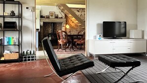 Een moderne woonkamer met een zwarte leren bank, een televisie en een eetgedeelte met houten stoelen en een tafel.