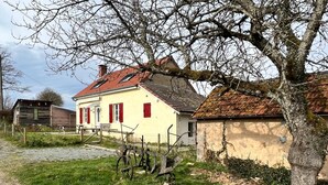 Een landhuis met een rode dakbedekking, een gele gevel en een houten omheining.