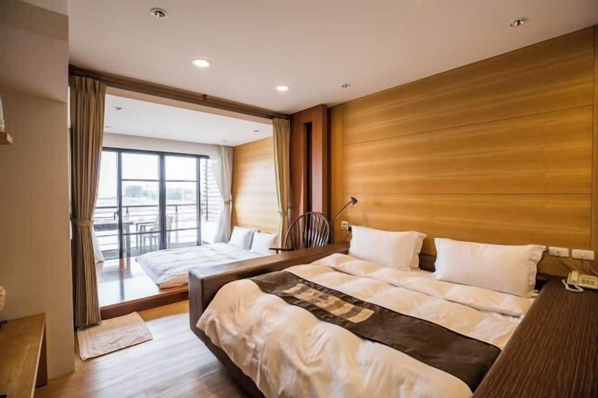 A modern hotel room with a large bed, a desk, and a view of the outdoors.