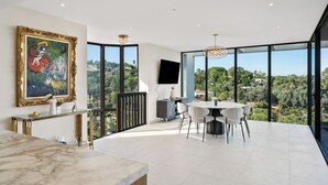 A spacious balcony with a dining area, a TV, and a painting on the wall.