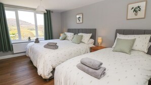 Een hotelkamer met twee bedden, een groot raam met uitzicht, een radiator en een nachtkastje met een lamp.