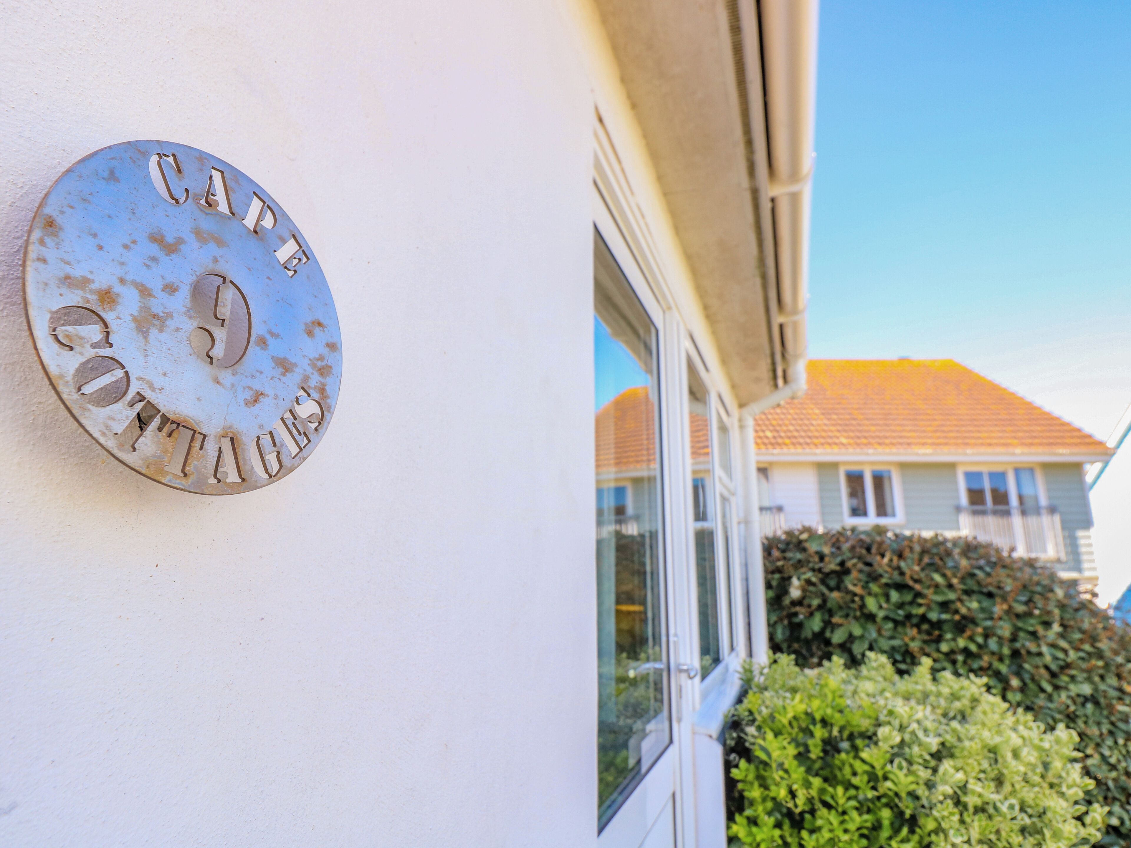 A metal sign on a building wall with the text "COTTAGES".