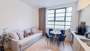 Ein gemütlicher, kompakter Wohnraum mit einer Couch, einem Esstisch und Stühlen.
