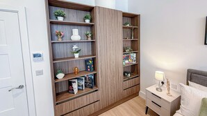 Ein modernes Schlafzimmer mit einer eingebauten Holzwandregal, einem Nachttisch mit Lampe und einem Bett mit weißer Bettwäsche.