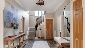 A spacious hallway with a wooden bench, a staircase, and a large abstract painting on the wall.