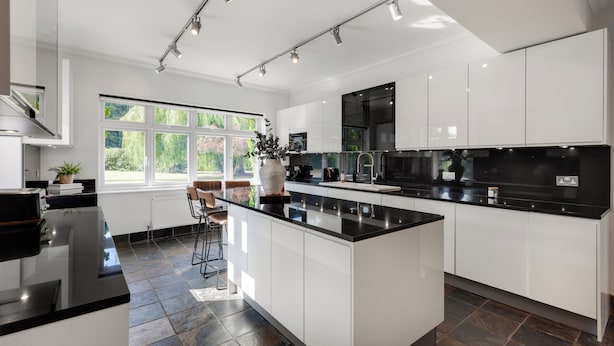 A modern kitchen with white cabinetry, a black countertop island, and a large window providing natural light.