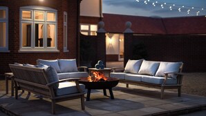 An outdoor patio with a fire pit, two sofas, and a table.