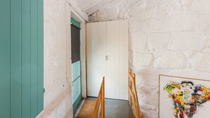 Un pasillo estrecho con una puerta blanca al final, una puerta verde a la izquierda y un marco de madera a la derecha.