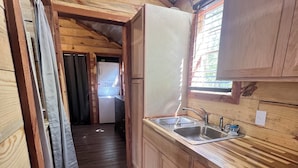 A narrow wooden kitchen with a sink, cabinets, and a window. - Cozy cabin with AC and WiFi in delightful Murfreesboro (Murfreesboro)