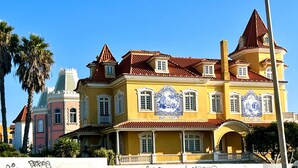 Un bâtiment historique à la façade jaune, doté de nombreuses fenêtres et d’un toit recouvert de tuiles rouges.