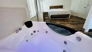Un dormitorio moderno con una cama grande, cabecera de madera, pared blanca y ventilador de techo.