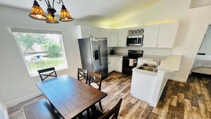 Una cocina moderna con armarios blancos, un refrigerador de acero inoxidable, un microondas y un lavabo.