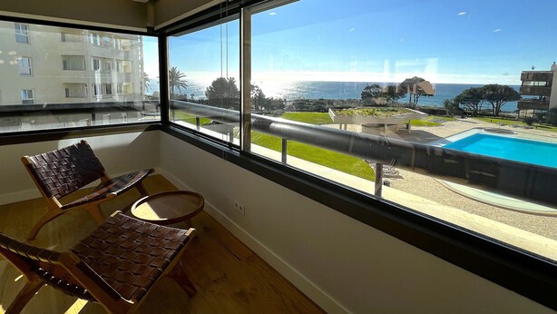 A balcony with a view of a swimming pool and a coastal landscape. - Atrium (Cascais)
