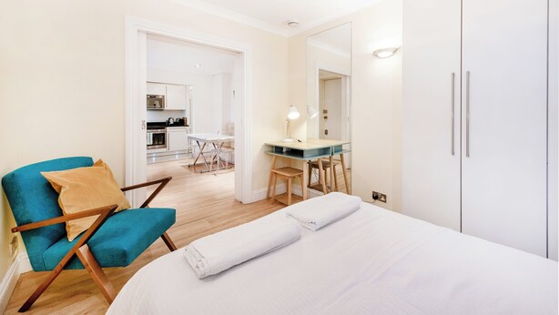 Una habitación de hotel con cama, escritorio, silla y armario.