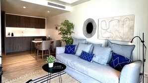 A modern living room with a grey sofa, a coffee table, and a dining area with a kitchen in the background. - D. Carlos (Lisbon)