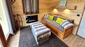 A wooden cabin room with a sofa, a bench, a TV, and a sign on the wall. - 100m from ski slopes, 1st floor, balcony, ski locker, 48m², Valfréjus (Valfréjus)