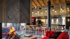 A modern interior with a fireplace, red seating, and a dining area with wooden furniture.