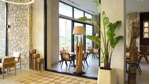 A spacious lobby with a checkered rug, wooden furniture, a large potted plant, and modern lighting fixtures. - Oricon Coast (Orikum)