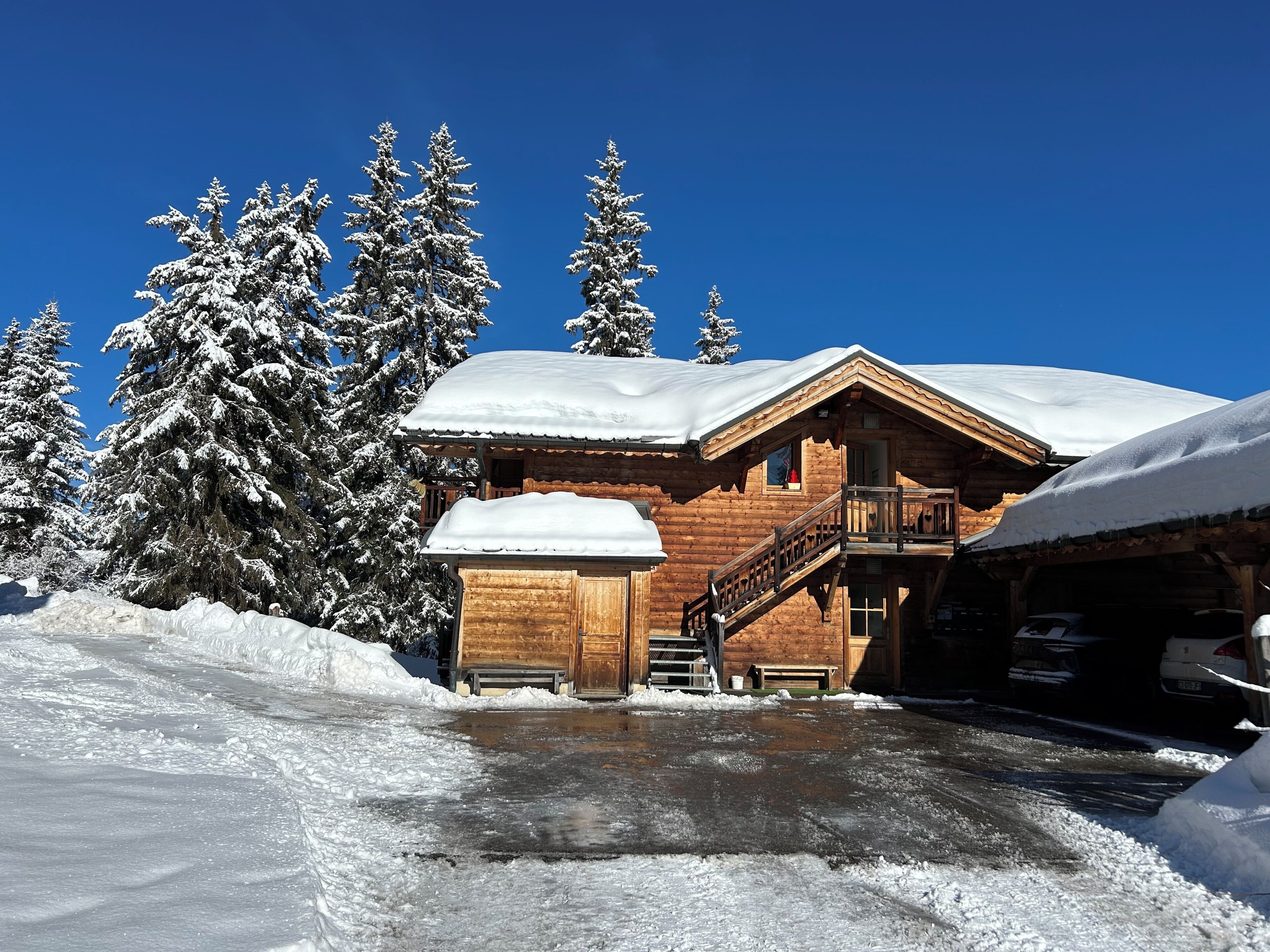 Una cabaña de madera con balcón, rodeada de árboles cubiertos de nieve.