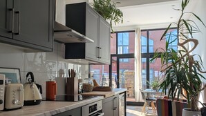 Et moderne køkken med mørke skabe, en central ø og et stort vindue med udsigt ud