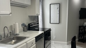 A modern kitchen with white cabinetry, stainless steel appliances, and a marble floor. - New Holley Rentals studio apartment in Vicksburg (Vicksburg)