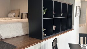 A bedroom with a bed, a black shelving unit, a desk, and a chair. - New Holley Rentals studio apartment in Vicksburg (Vicksburg)