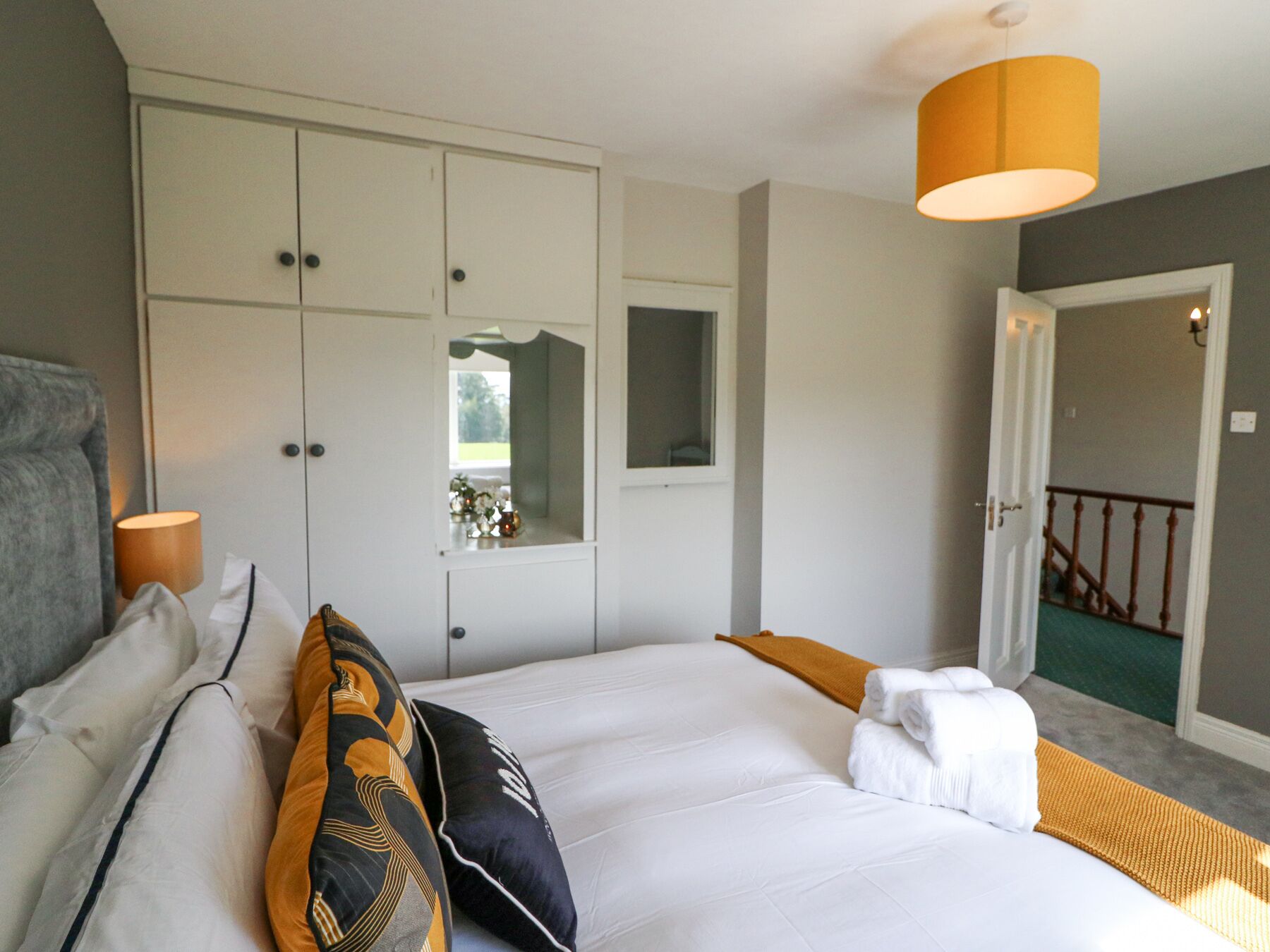 Un dormitorio con una cama grande, un armario blanco y un espejo.