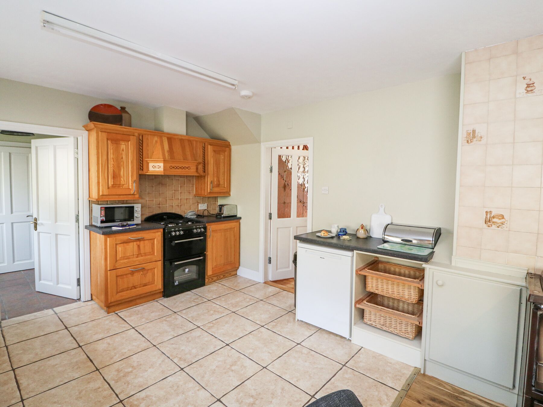 A compact kitchen with wooden cabinets, a microwave, a stove, and a small refrigerator.