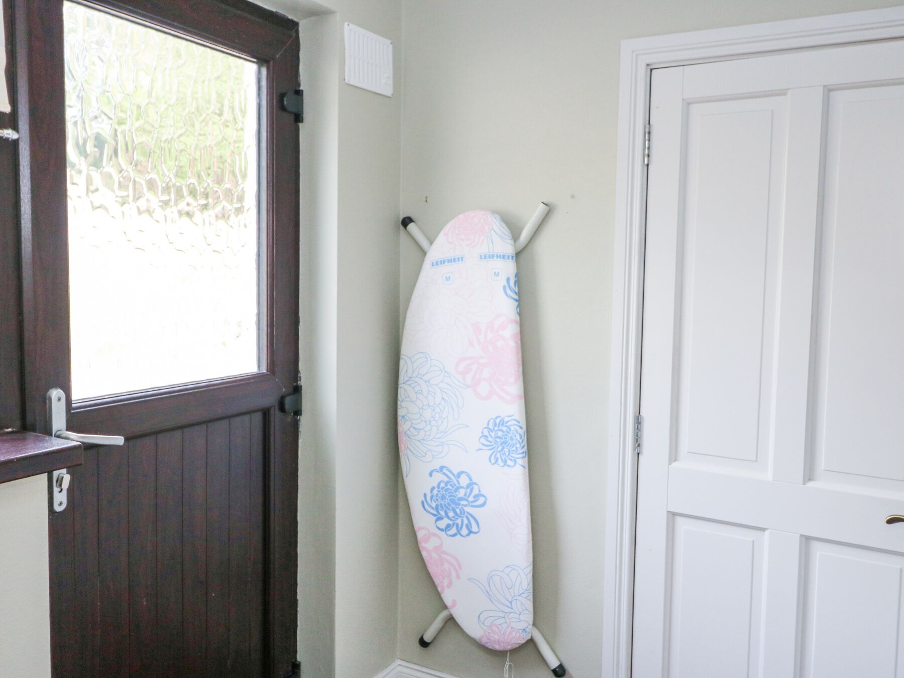 A surfboard leaning against a wall in a room with a door and a window.