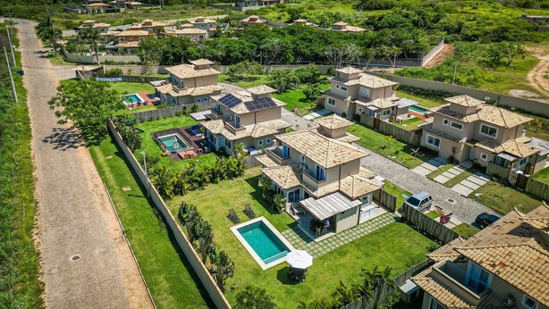 A residential area with multiple houses, a swimming pool, and a clear view of the ocean. - Bz83 Casa no Centro Piscina e 4 suítes (Buzios)