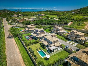 Un barrio residencial con varias casas, una piscina y una vista despejada del océano.